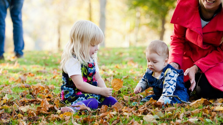 Two girls playing with autumn leaves in the gardens at Cliveden, Buckinghamshire.